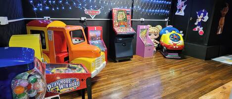 A children's play area with arcade games, a toy car, and plush toys.