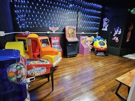 A children's play area with arcade games, a toy car, and plush toys.