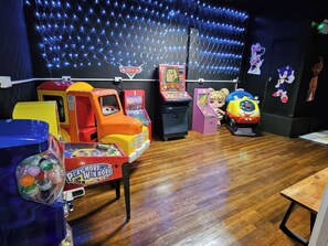 Un área de juegos infantiles con juegos de arcade, un coche de juguete y peluches.
