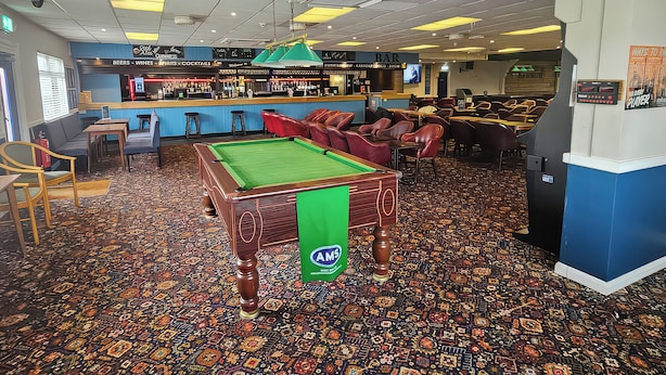 A pool table with a green cloth, a bar area with a counter and stools, and a patterned carpet. - Watersmeet - 85 @ Park Avenue Holiday Village (Sheerness)
