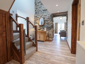 Eine Treppe mit Holellbrailen, einer Steinwand und einem Küchenbereich mit einem Holsschrank und einem Spiegel.