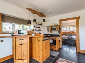 A kitchen with wooden cabinets, a central island, pendant lighting, and a view to the outside. - The Lodge, Chester: Cozy Retreat (Chester)