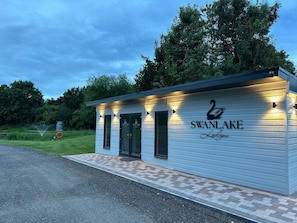 Un pequeño edificio de una sola planta con un letrero que dice 'SWAN LAKE Lodge' y un logotipo de cisne.