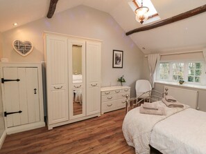 Ein Schlafzimmer mit Bett, Kleiderschrank, Spiegel, Stuhl und Fenster.