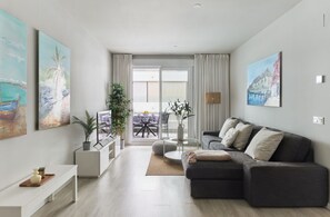 Ein modernes Wohnzimmer mit grauem Sofa, einem Couchtisch und einem Essbereich mit Tisch und Stühlen.