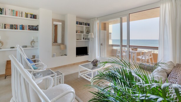 Un salon moderne doté d’une grande fenêtre donnant sur la mer, d’une bibliothèque, d’un téléviseur à écran plat et d’un coin salon avec vue.