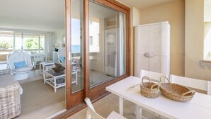 Un balcon avec une table blanche, des paniers en osier et des chaises en osier blanc.