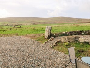 A gravel patio with a stone structure, a chair, and a table. - Shepherds Retreat Glenlark - Cozy Getaway (Omagh)