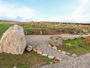 A rural landscape with a large rock, a gravel path, and a mound in the distance. - Shepherds Retreat Glenlark - Cozy Getaway (Omagh)
