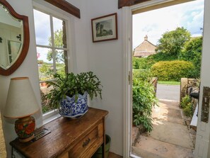 A room with a wooden dresser, a blue and white vase with green plants, a mirror, and a framed picture on the wall. - Sally's Cottage, Carleton-In-Craven (Skipton)
