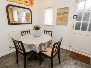 A dining area with a round table, chairs, a vase with flowers, a mirror, and a door with frosted glass panels.