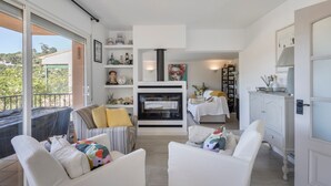 Un salon moderne avec une cheminée, des meubles blancs et une vue sur l’extérieur.