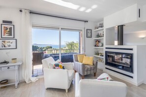 A modern living room with a balcony, white furniture, and a fireplace. - Beautiful House with Sea Views (Begur)