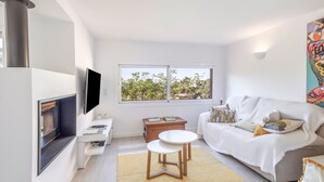 Un salon moderne avec un téléviseur à écran plat, un canapé, une table basse et une cheminée.