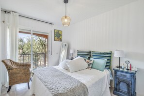 A bedroom with a bed, a chair, a nightstand, and a view of the outdoors. - Beautiful House with Sea Views (Begur)