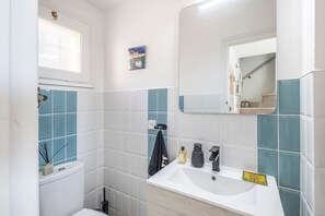 A bathroom with a toilet, sink, mirror, and blue-tiled walls. - Beautiful House with Sea Views (Begur)