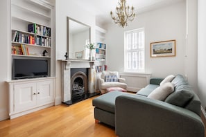 A living room with a fireplace, bookshelves, a sofa, and a television. - 32 Park Street, Windsor, Berkshire (Windsor)