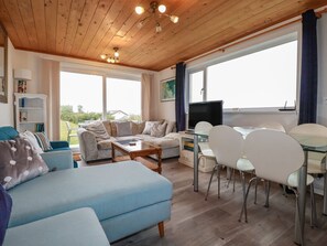 A living room with a sofa, coffee table, and dining area with chairs and a table. - 38 Surf View, Newquay (Newquay)