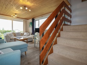 A modern interior with a wooden staircase, a sofa, a coffee table, and a view of the outdoors. - 38 Surf View, Newquay (Newquay)