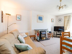 Ein Wohnzimmer mit Sofa, Fernseher, Kamin und Essbereich.