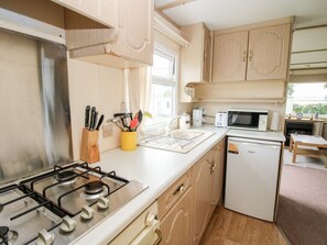 A compact kitchen with a gas stove, microwave, and dishwasher. - 7 Old Orchard, Much Wenlock (Much Wenlock)