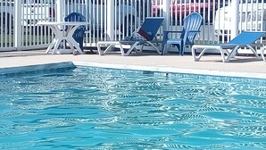 A swimming pool with lounge chairs and a white fence. - Gorgeous 3-bedroom apartment in adorable Harrington perfect for relaxing (Harrington)