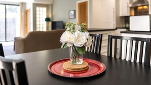 Ein Esstisch mit Blumen in einer Vase, einem Teller mit einem Keks und Stühlen in einer modernen Küche.