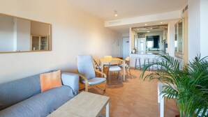 Een moderne woonkamer met een bank, stoelen, een tafel, en een keuken in de achtergrond.