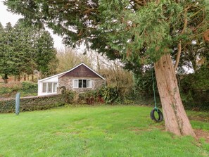 A house with a stone facade, a white window, and a swing hanging from a tree. - Priory House Cottage, Barnstaple (Barnstaple)