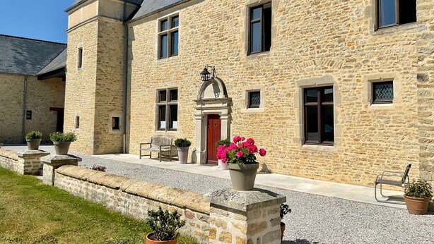 A stone building with a red door, multiple windows, and a small balcony. - Baie des Veys Cottage near Utah Beach (Brucheville)