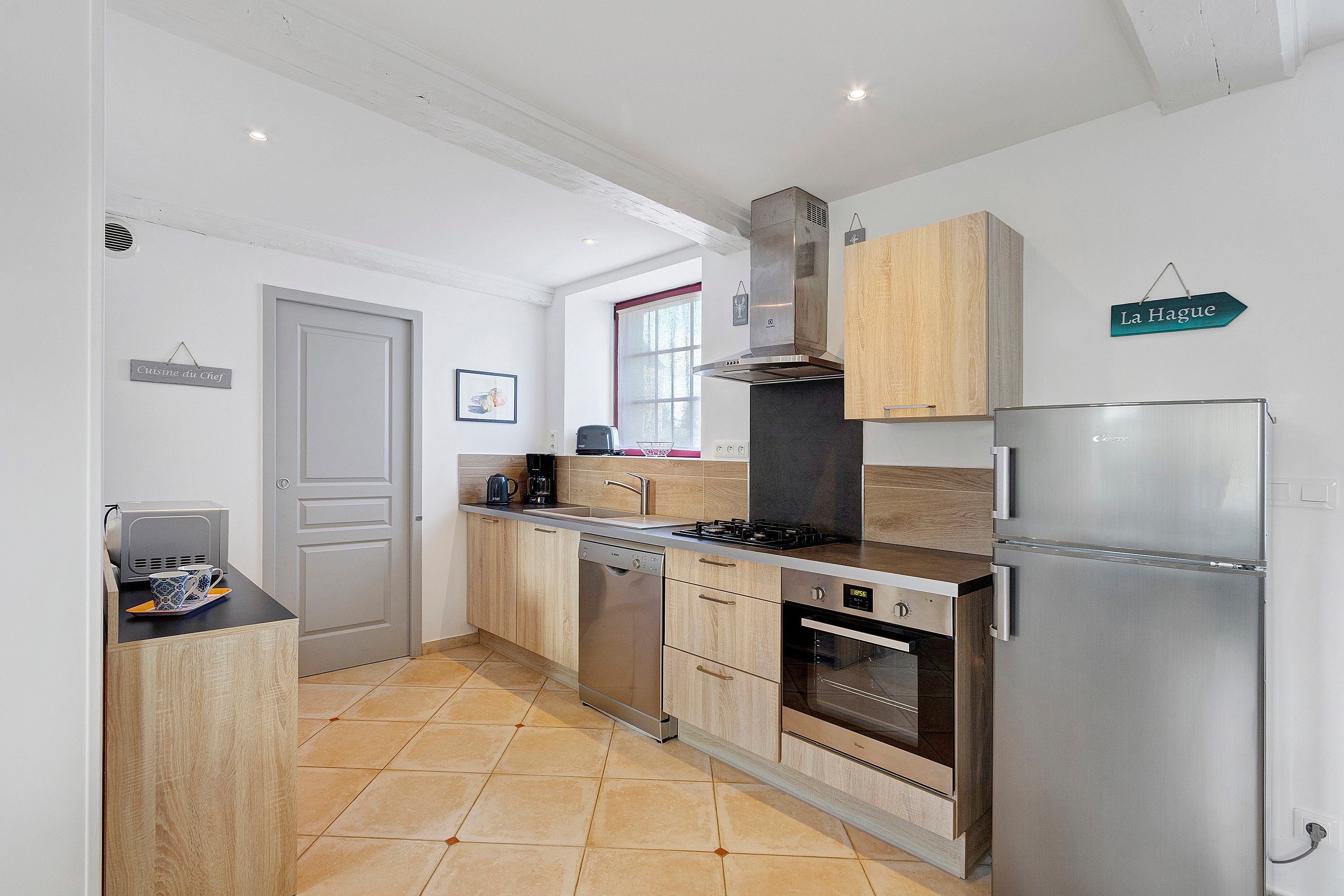 A modern kitchen with a stainless steel refrigerator, a built-in oven, a dishwasher, and a gas stove.