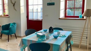 A dining area with a table set for four, chairs, a red door, windows, and a sign reading 'Barfleur'. - Baie des Veys Cottage near Utah Beach (Brucheville)