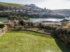 A grassy area with a wooden fence, a river, and a town in the background. - Estuary View, Newton Ferrers (Plymouth)