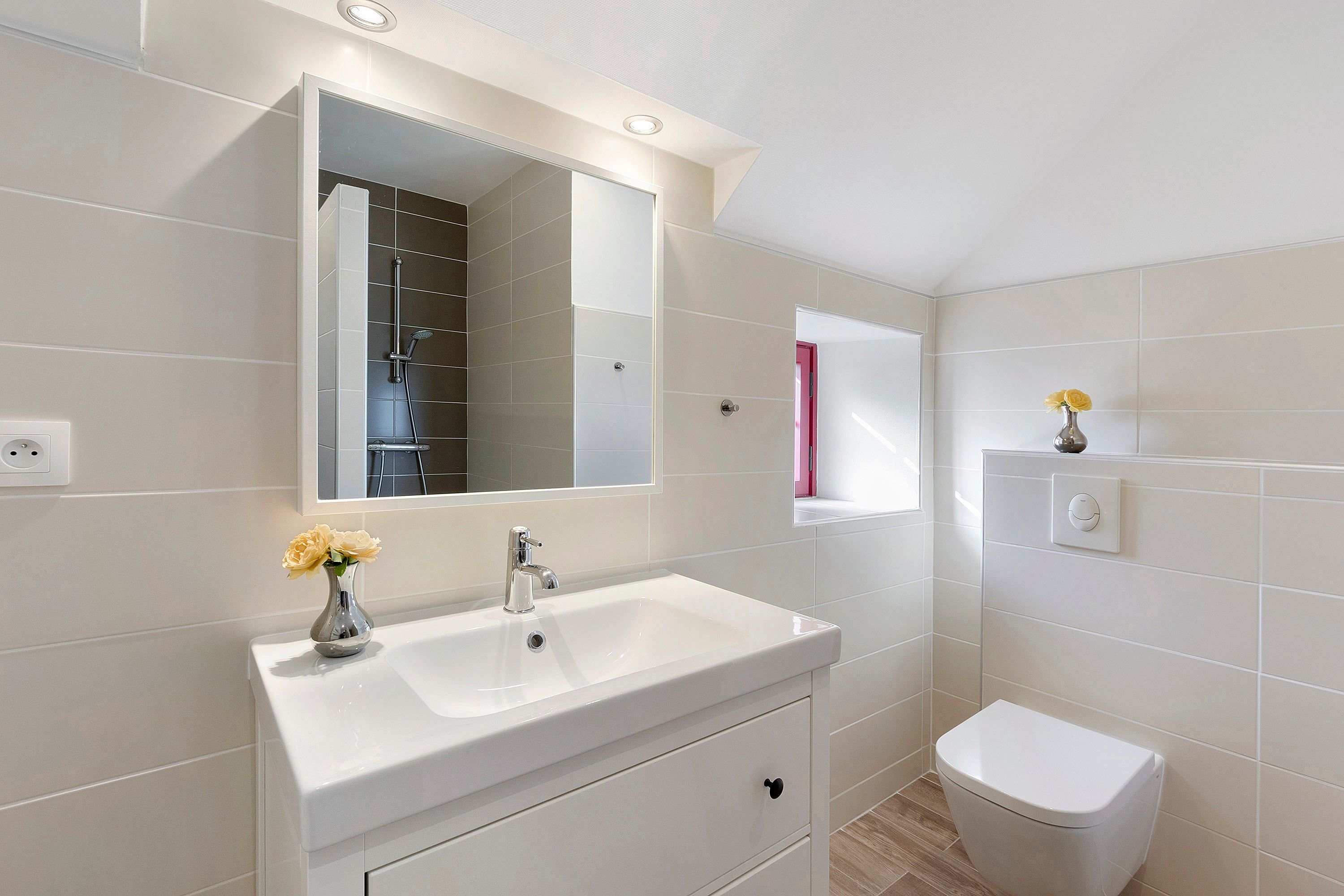 A modern bathroom with a white sink, mirror, and toilet.