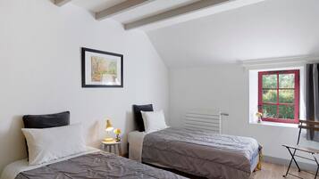Een slaapkamer met twee bedden, een raam met rode randen, een radiator en een lijst met een afbeelding aan de muur.
