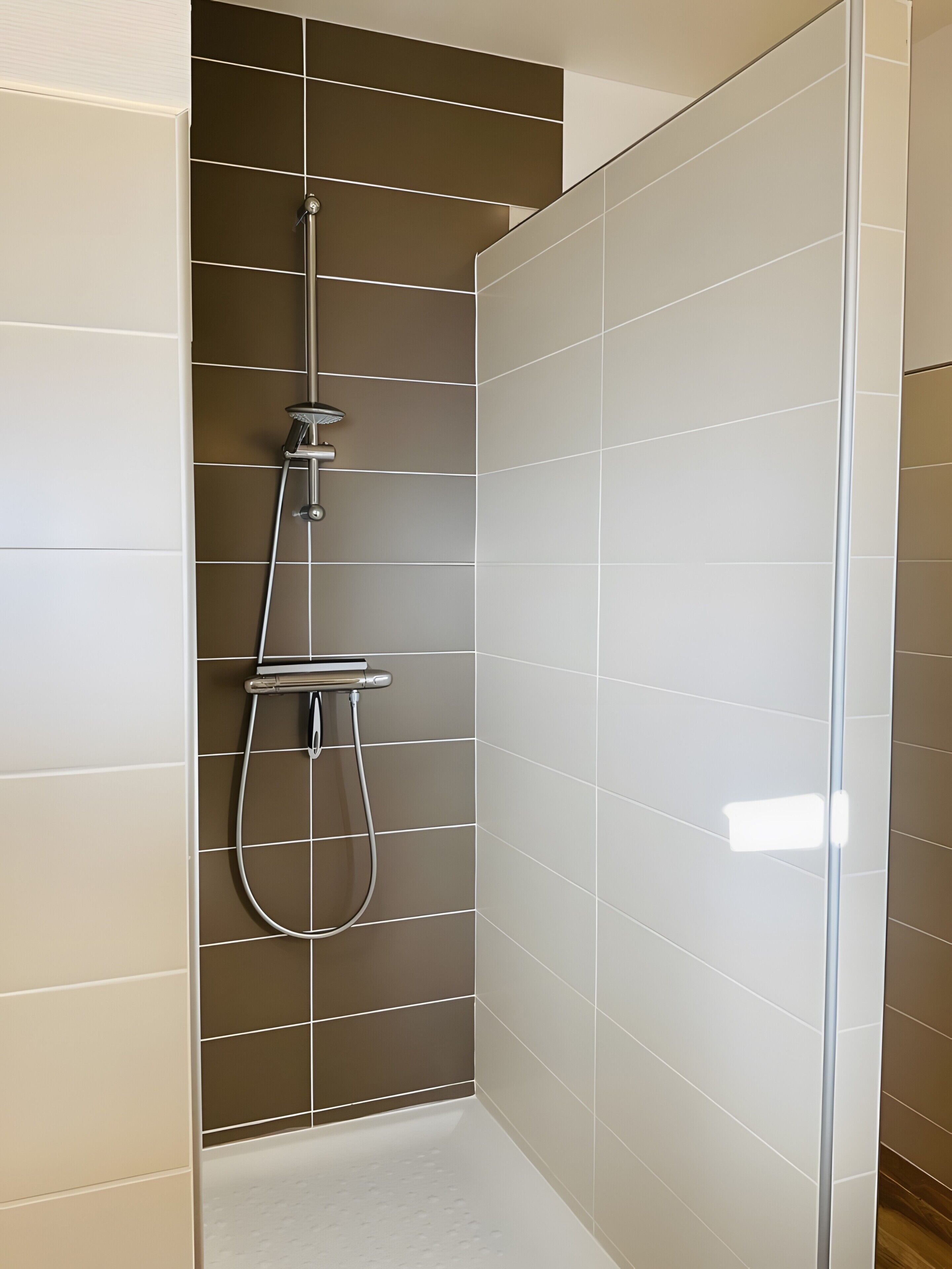 A shower with a handheld showerhead and a wall-mounted faucet.