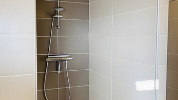 A shower with a handheld showerhead and a wall-mounted faucet.