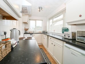 A modern kitchen with white cabinets, a black countertop, a kettle, a toaster, and a coffee maker. - Phloxhaven: A Charming Retreat in Reedham (Norwich)