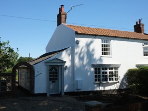 A white building with a tiled roof, a brick chimney, and a number '5' on the door. - Phloxhaven: A Charming Retreat in Reedham (Norwich)
