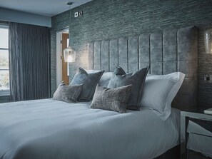A modern bedroom with a large bed, a textured wall, and a hanging light fixture. - Edgar House, Chester, Cheshire (Chester)