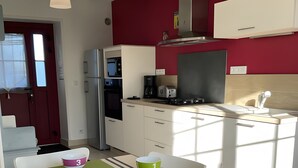 Une cuisine moderne avec des meubles blancs, un mur rouge et une table à manger agrémentée de bols numérotés.