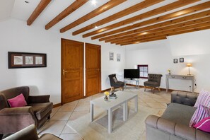 A living room with a sofa, armchairs, a coffee table, a TV, and a fireplace. - Gîte Manoir de Beaucron for 6 Guests (Brucheville)