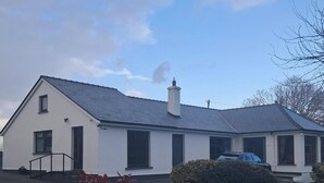 Un bâtiment blanc avec un toit gris, un mur en pierre et une allée.