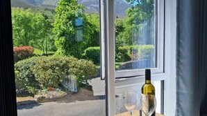 Une table avec une bouteille de vin, un verre et une assiette de fraises et de fromage.