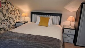 Une chambre d’hôtel comprenant un lit, deux tables de chevet, une commode, une lampe, un tiroir et un rideau.