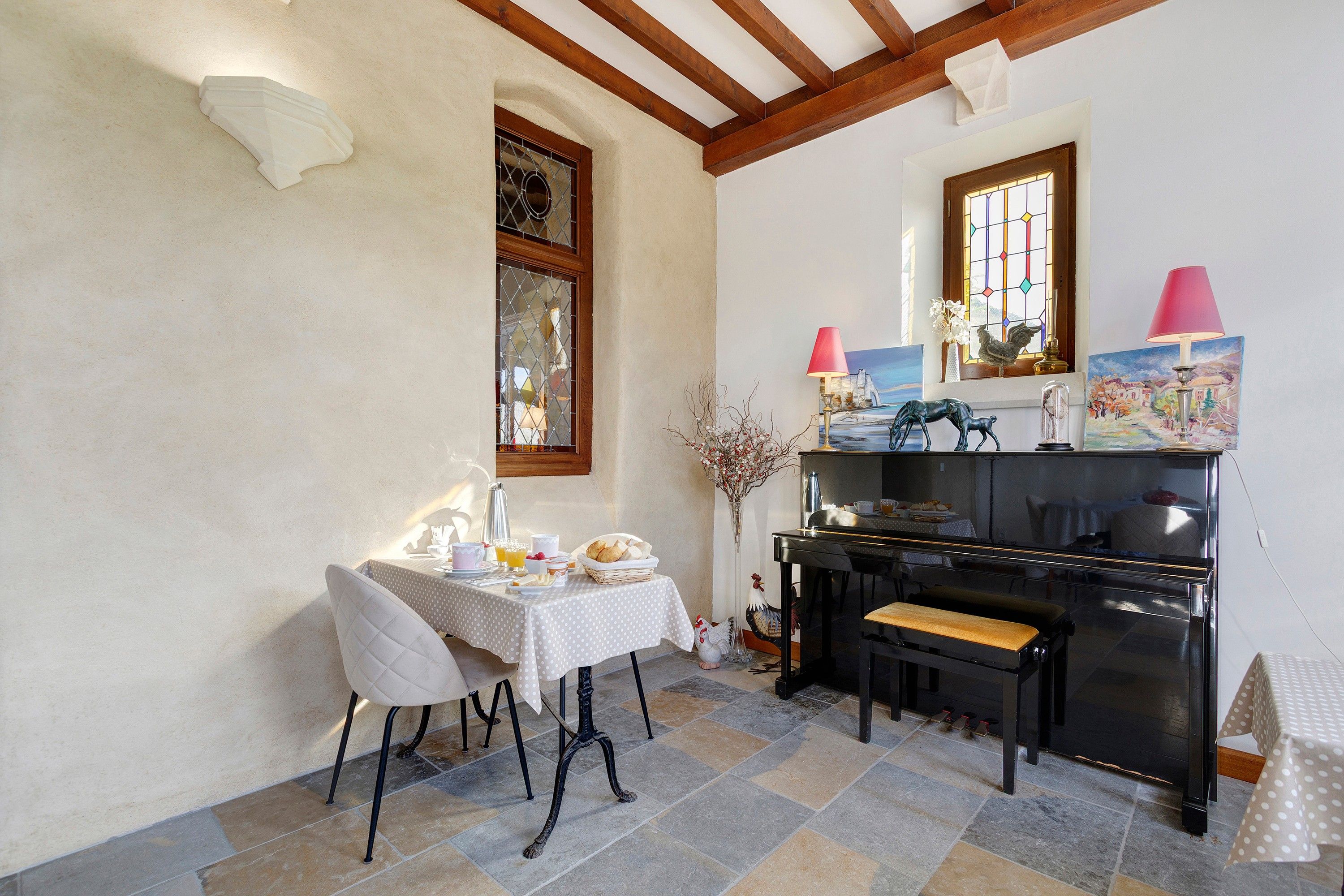 Zona pranzo con tavolo apparecchiato per la colazione, una panca e un pianoforte.