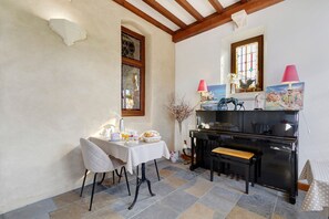 Un coin repas avec une table mise pour le petit-déjeuner, un banc et un piano.
