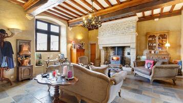 A traditional room with exposed wooden beams, a fireplace, and vintage furniture.