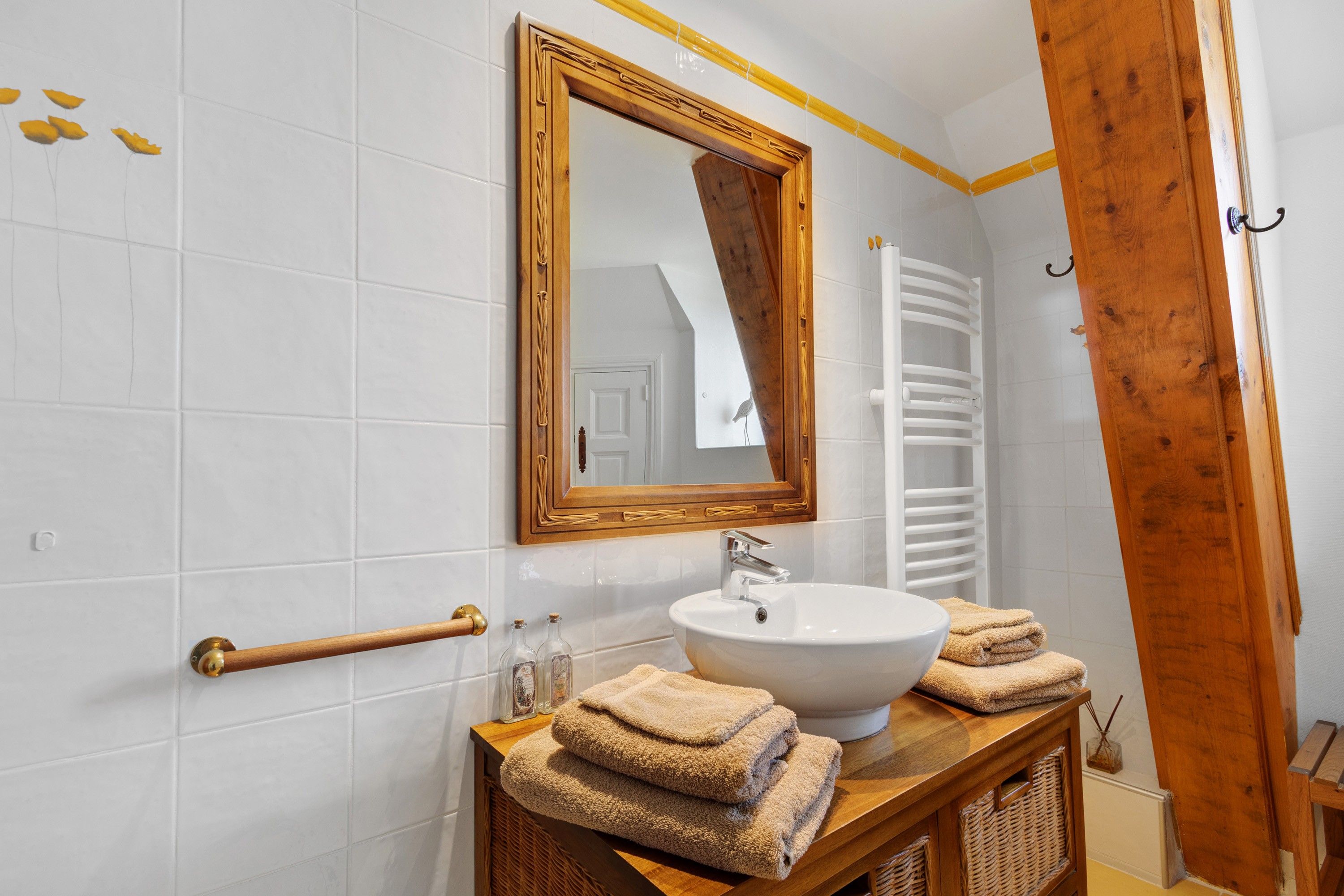 Une salle de bain avec un lavabo blanc, un meuble-lavabo en bois et un miroir avec un cadre en bois.