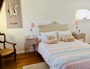 Une chambre à coucher comprenant un lit, deux tables de chevet, une chaise et une lampe fixée au mur.